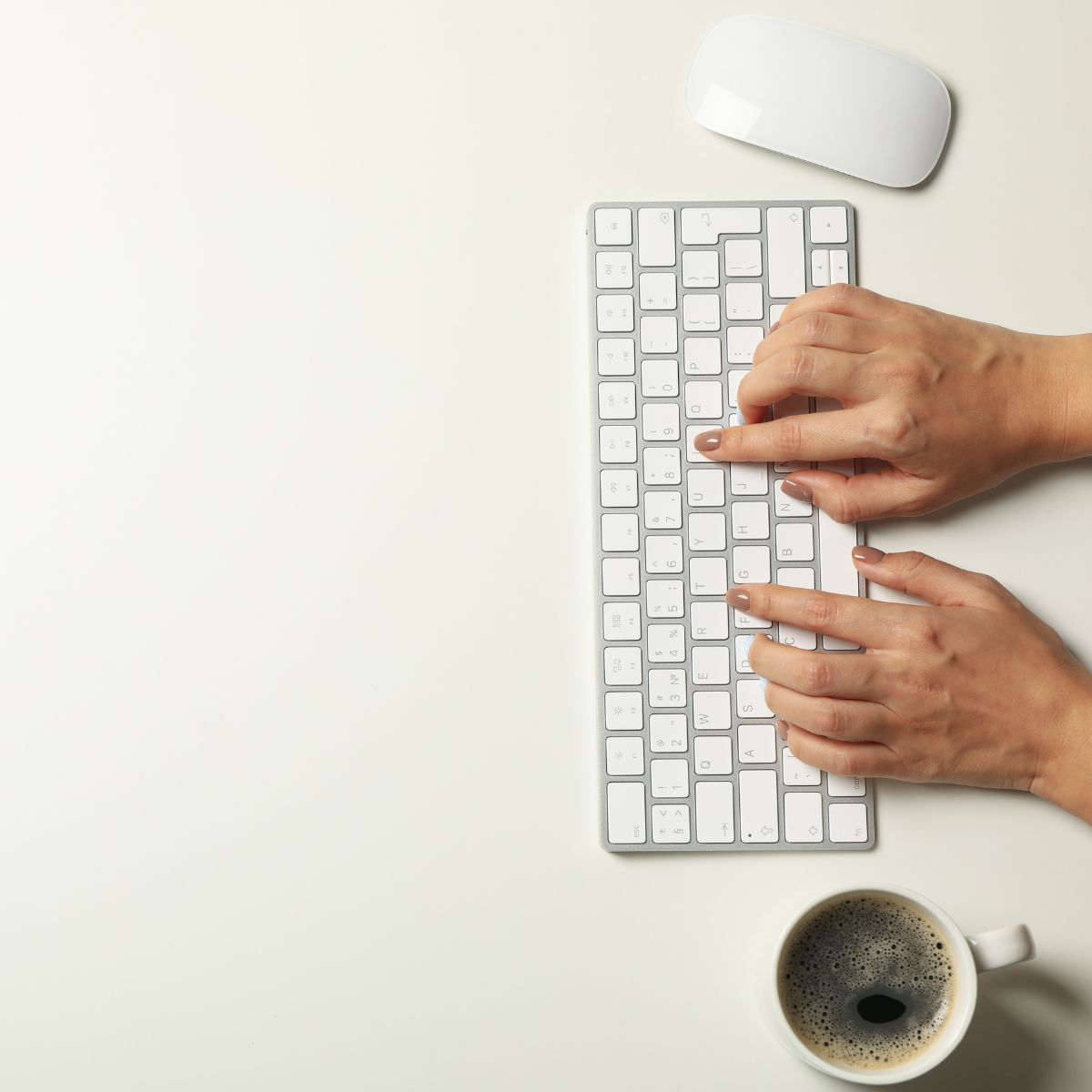 Hands typing on keyboard with mouse and coffee - representing active work